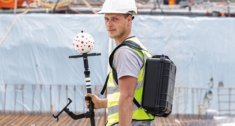 Ouvrier de chantier portant un casque blanc et utilisant la Leica iCON vPole sur le chantier.
